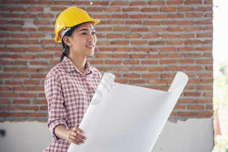 作坊企业家女建筑工程师在地身戴安全白色钢帽的建筑工场薪女程师土木带有硬帽子安全头盔的女建筑工程师概念a妇女建筑工程师地点图片