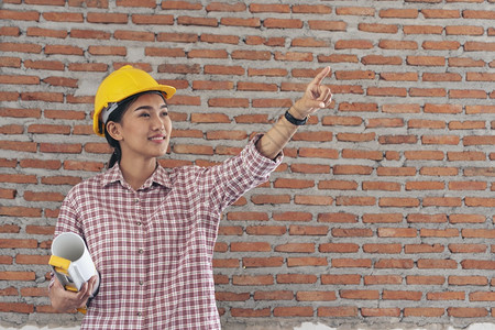 写作女建筑工程师在地身戴安全白色钢帽的建筑工场薪女程师土木带有硬帽子安全头盔的女建筑工程师概念a妇女建筑工程师企业家作坊图片