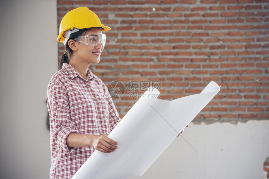 承包商格子项目女建筑工程师在地身戴安全白色钢帽的建筑工场薪女程师土木带有硬帽子安全头盔的女建筑工程师概念a妇女建筑工程师图片
