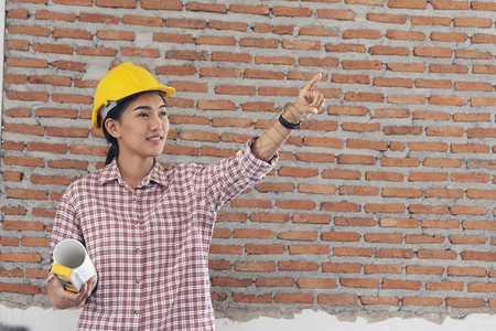 蓝图女建筑工程师在地身戴安全白色钢帽的建筑工场薪女程师土木带有硬帽子安全头盔的女建筑工程师概念a妇女建筑工程师人们金属丝图片