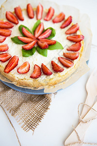 糖果桌子面粉用草莓装饰的非常漂亮夏季芝士蛋糕站在白色的木桌上非常漂亮的用草莓装饰夏季芝士蛋糕图片