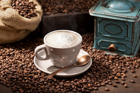 老的热咖啡杯卡布奇诺或拿铁烤豆和老研磨机瓷作品图片