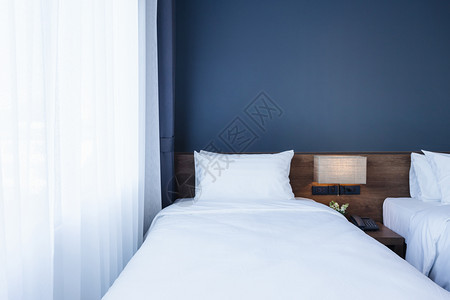睡觉柔软的旅行在床上装饰的白色枕头上加灯和在旅馆室内卧安装数字电话的白枕头图片