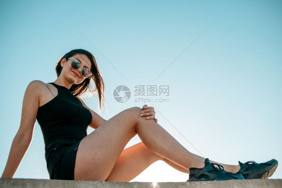 蓝色的城市最佳穿着黑色运动鞋短裤和的头发女孩坐在一栋高楼屋顶上图片