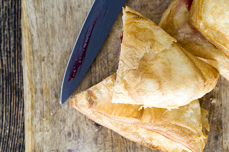 脂肪里面有樱桃果酱的美味炸包子在厨房里闭着一个面包用刀切开一小块果饼左上饮食一顿饭图片
