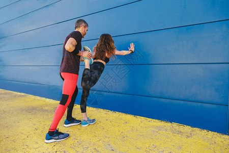 年轻情侣在蓝墙前拉一起然后奔跑运动白种人活力图片