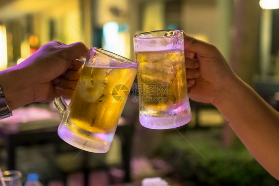 两杯啤酒在朋友之间一起欢呼在低光酒吧的朋友和餐厅放松饮酒的概念男贮藏啤酒草案图片