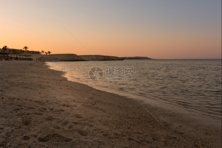 岛海洋日落时美丽的埃及海滩背景有棕榈树和阳伞巡航图片