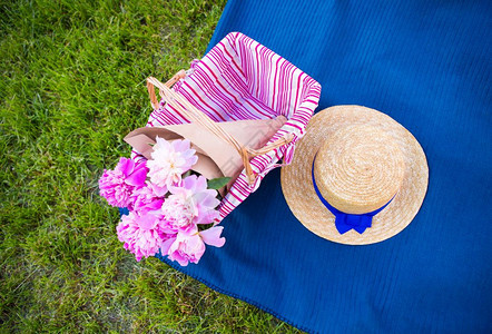浪漫的户外葡萄酒一篮子盛着美丽的鲜花和草帽在一格亮丽的夏日野餐上图片
