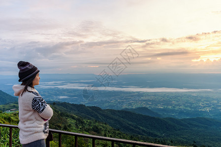 旅游穿着毛衣的女游客在清晨PhuThapBoekViewpointPhetchabun高峰日出时站立观察森林和山区美丽的自然景观图片