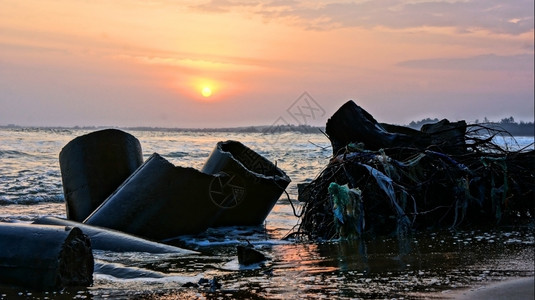 海滨岸线边侵蚀浪摧毁堤气候变化影响这是未来全球环境问题日落时太阳下浅滩的断水被毁坏在日落时晒太阳之下越南图片