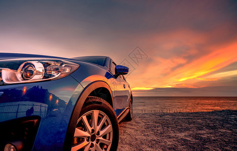 蓝紧凑的SUV车有运动和现代设计由海滩停靠在日落绝夕阳与电动汽车技术混合设施以及电动汽车技术辆停放牌泊空间汽工业景观电的夏天图片