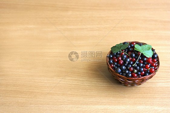 切割摄影植物黑浆果和红花草在旧木质表面的棕色圆篮子里图片
