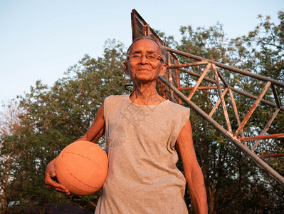 参加体育运动的亚洲老年男子在夏季日一个户外篮球法庭举行比赛看摄影机健康生活方式和保健概念HitalthViewsandHealt图片