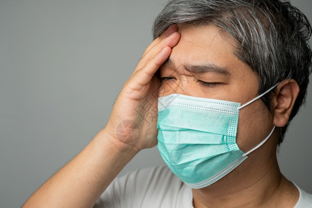 男生病的过敏身戴医疗面罩的亚洲病男子用手将头的痛抓在部保护大流行冠状和呼吸道疾概念图片