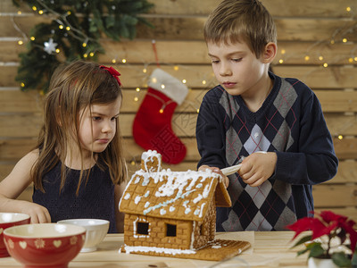 厨房女儿一位年轻兄弟姐妹在圣诞节前夕家里装饰姜饼屋的照片该来自BeableBread图片