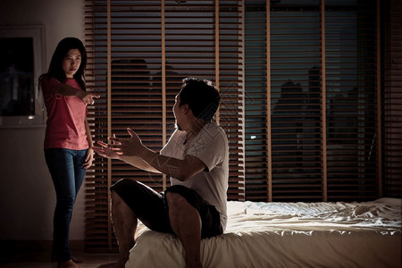 西班牙裔丈夫和妻子在黑暗卧室的床上争吵环境低轻概念戏剧情节深刻气氛极差低的亚洲图片