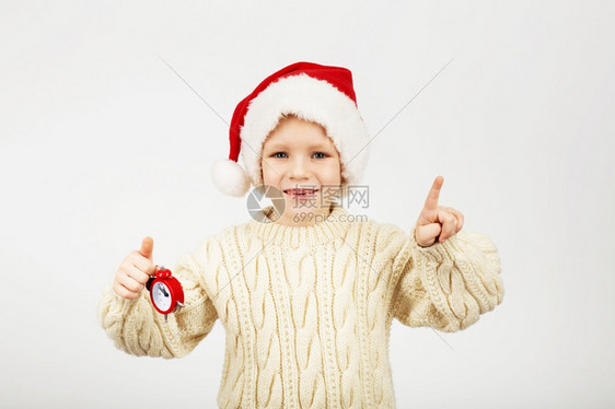 快乐的美丽小男孩在新年和圣诞节概念的白背景下戴着圣诞老人帽子的景象新微笑十二月图片