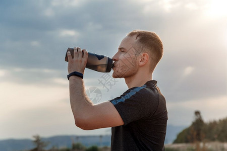 热恢复茶点一名年轻白人男子穿着黑色T恤和短裤的肖像在培训后或前从瓶子中饮用水图片