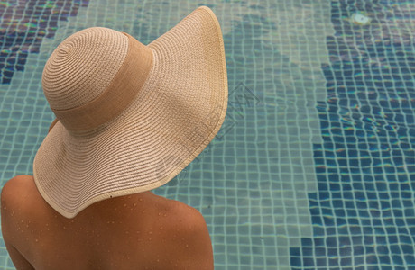 戴着帽子在游泳池放松的年轻女人图片