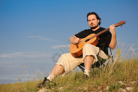 玩自由男人户外弹声吉他在日落家户外光线图片