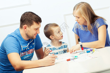 随意的绘画年轻父母与儿子一起在桌边画男图片