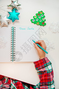年轻的亲爱圣诞老人信贺卡一个拿着笔的孩子在木制背景上的白纸写字带有新年装饰童梦想的礼物新年概念亲爱的圣诞老人信贺卡一个拿着笔的孩图片