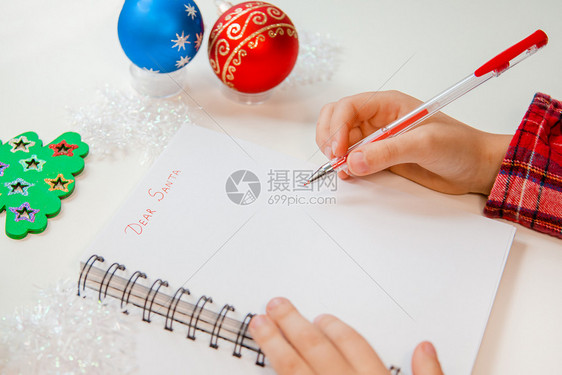 铅笔亲爱的圣诞老人信贺卡一个拿着笔的孩子在木制背景上的白纸写字带有新年装饰童梦想的礼物新年概念亲爱的圣诞老人信贺卡一个拿着笔的孩图片
