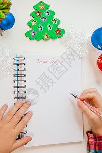 装饰风格克劳斯假期亲爱的圣诞老人信贺卡一个拿着笔的孩子在木制背景上的白纸写字带有新年装饰童梦想的礼物新年概念亲爱的圣诞老人信贺卡图片