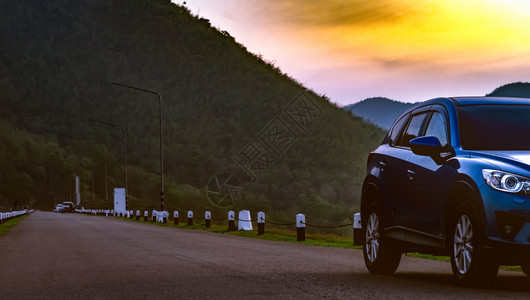 蓝色SUV车停在山前面的沥青路上该车于清晨与日出天空一起停在公园早的山车前面蓝色的自然奢华图片