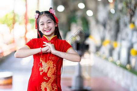 身着中华新年节国青春红传统香藏装饰的可爱亚洲小女孩长得一脸美丽的笑并戴着彩礼快乐的幸福肖像图片