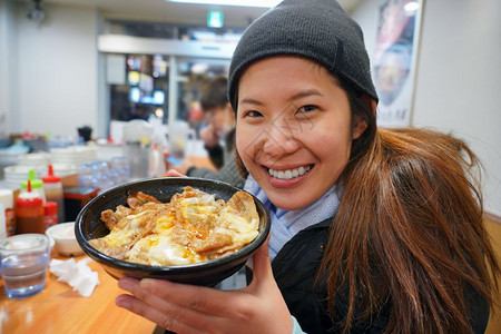 午餐亚洲年轻女享受日本菜在鱼市TokyoJapan的碗里有大米和烧烤牛肉煎鸡蛋和奶酪视频博客温泉图片