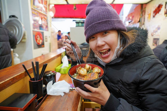 亚洲年轻女享受日本菜美食在鱼市东京日本的碗里有大米和虾烤的保持美丽图片