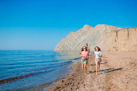 爸和女儿的家人在海滩上奔跑小女孩和快乐的爸在海滩度假期间玩得开心了绿松石愉快乐趣图片