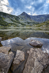 寒意高山绿色湖上的美日风景在前垂直视图处有岩石的山湖图片