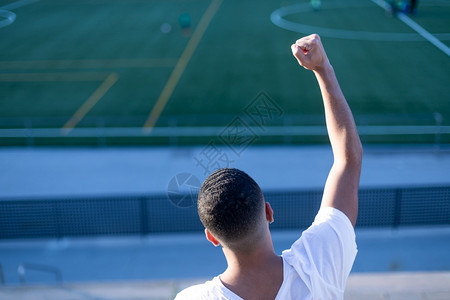 手臂一个穿着T恤和牛仔裤的英俊男青年独自坐在体育场运动台情感球图片