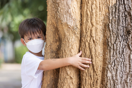 爱白种人一个戴着面具的男孩站拥抱一棵大树看着照相机健康图片
