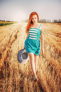 步行人们蓝色的红发女孩在草地美丽的女中享受大自然穿着蓝礼服的红头发女孩在太阳光的花朵上行走图片