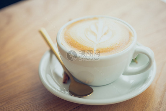 咖啡是用古老风格在木制桌上的拿铁取自最上风见牛奶泡沫的花霜香气热桌子图片