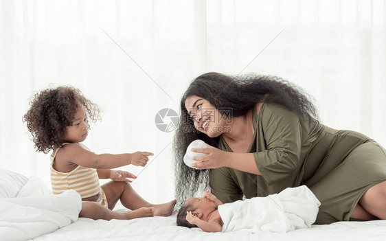 黑色的非洲人妈在家卧室照顾自己的小儿子和女非洲黑人母亲在卧室里照顾她的儿子和小女快乐的舒适图片