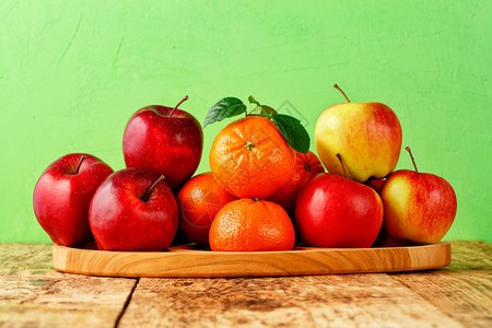 农村甜的点红熟苹果和绿叶橘子放在浅色背景的旧木桌上托盘图像有复制空间红熟苹果和绿叶橘子放在浅色背景旧木桌上的托盘图片