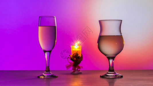 问候绿色红酒杯两白葡萄和桌上的蜡烛粉红色背景两杯白葡萄酒和桌上的蜡烛图片
