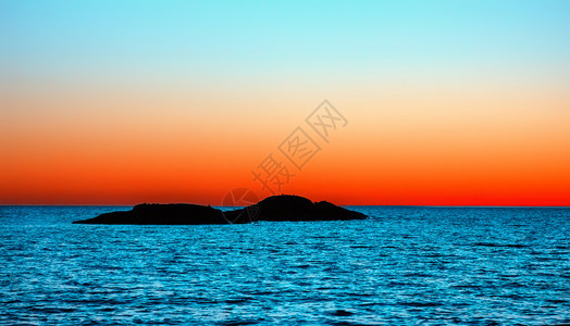 一小岛位于地平线背景将橙色和绿宝石天空与橙色水和蓝夜海景的色表面隔开在一小岛的奥尼加黑浅滩湖上白夜视暗海景风无云遥远图片