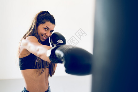 运动在拳击学校年轻女子训练拳击打重袋手上戴套的拳击重跆道图片