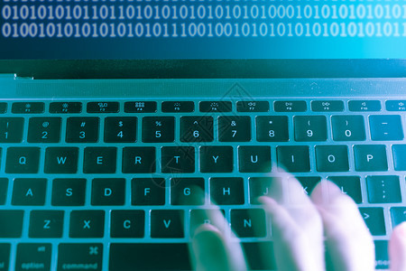 计算机程序员或黑客在笔记本电脑键盘上打印代码以破入秘密组织系统阴影互联网安全图片