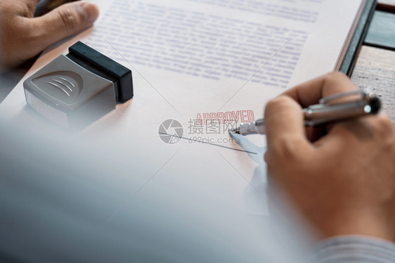 橡胶或者贴纸在核准贷款文件协议律师亲手概念的印章后男子在证书合同中签字或男高级商人在批准贷款文件协议书上加盖印章后图片