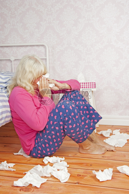 孤独情感皱着眉头有粉色睡衣和纸巾的生病妇女坐在地板上躺床图片