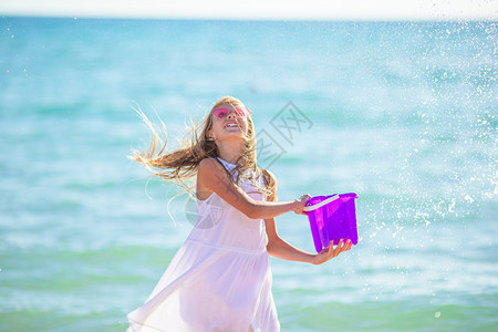 小女孩在热带海滩上玩浪游戏在卡利比恩度假期间与一个水桶和小可爱女孩一起在海滩玩岸波浪异国情调图片