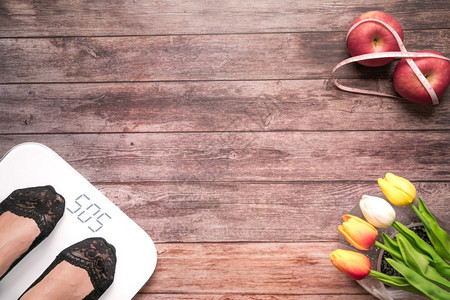 身体新鲜的水果妇女脚站着规模饮食红苹果与木质背景健康和生活概念的测量胶带捆绑在一起木质背景上有女双脚按比例表站立和饮食红苹果图片