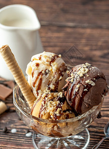 舀倒了质地巧克力奶油和焦糖罗马人冰淇淋在玻璃碗里加了栗子和巧克力酱图片
